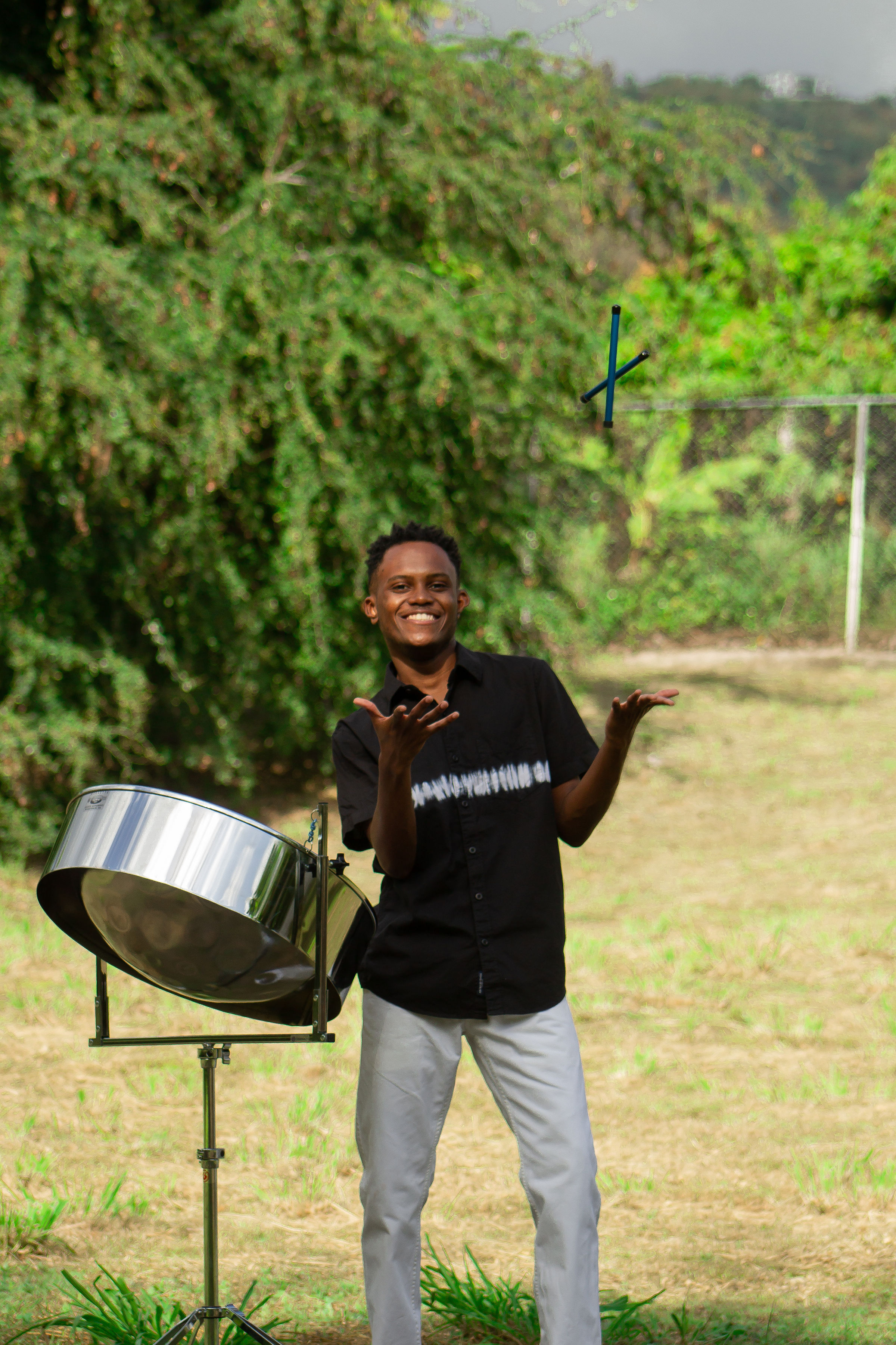 Milton tossing his sticks beside his Low C Tenor steelpan from Mannette Instruments
